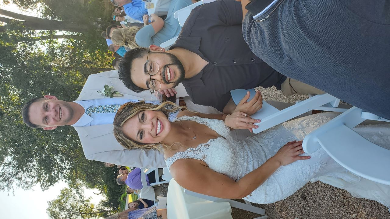 The bride and groom posing with a guest at their wedding reception.